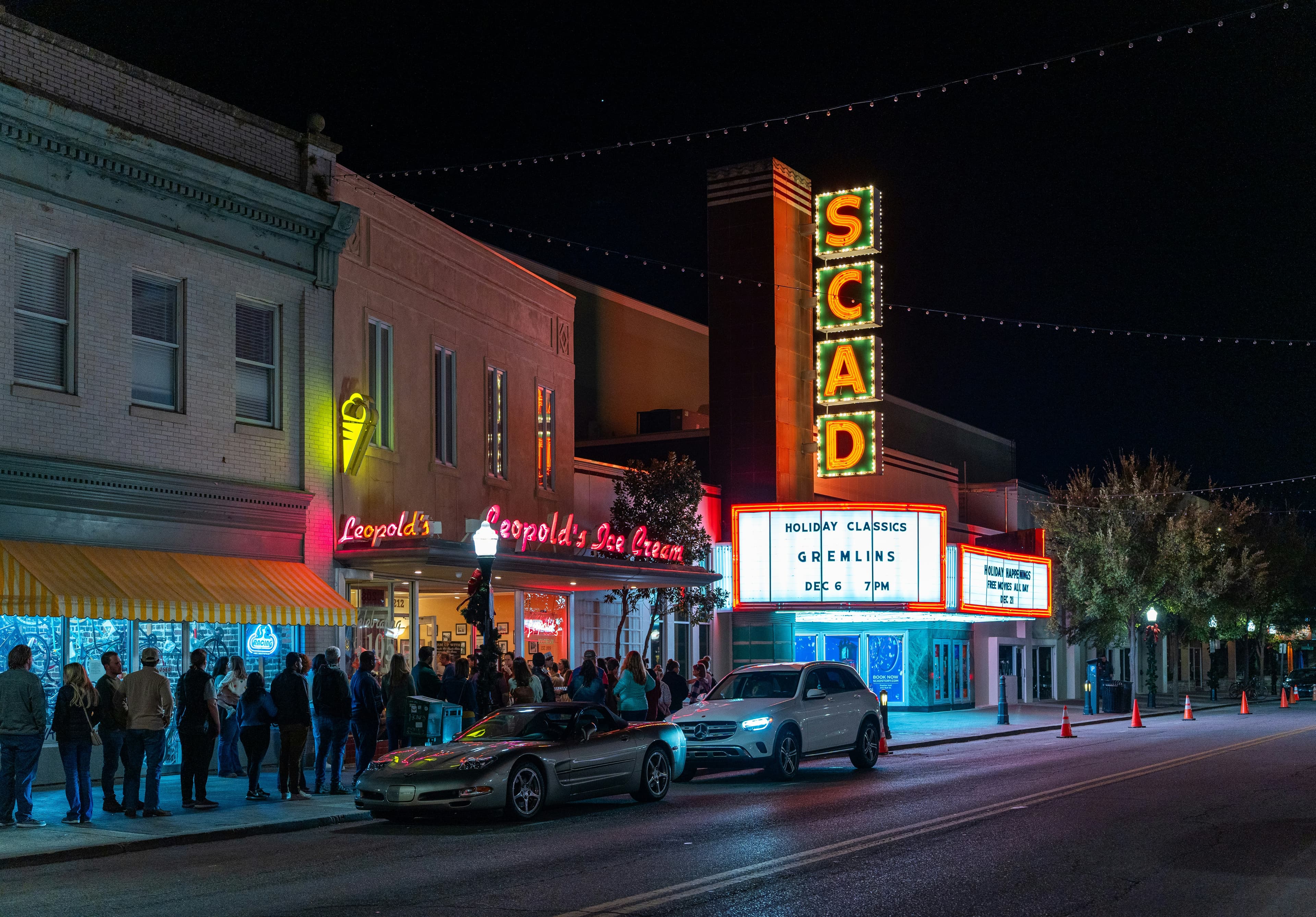Crowds line up outside Leopold's Ice Cream beside the illuminated SCAD theater at night.